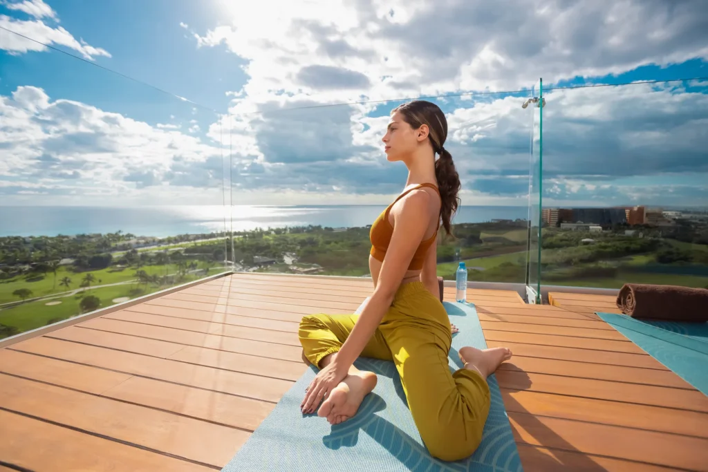 Woman practicing yoga on a rooftop deck with ocean views at Hyatt Vivid Grand Island.