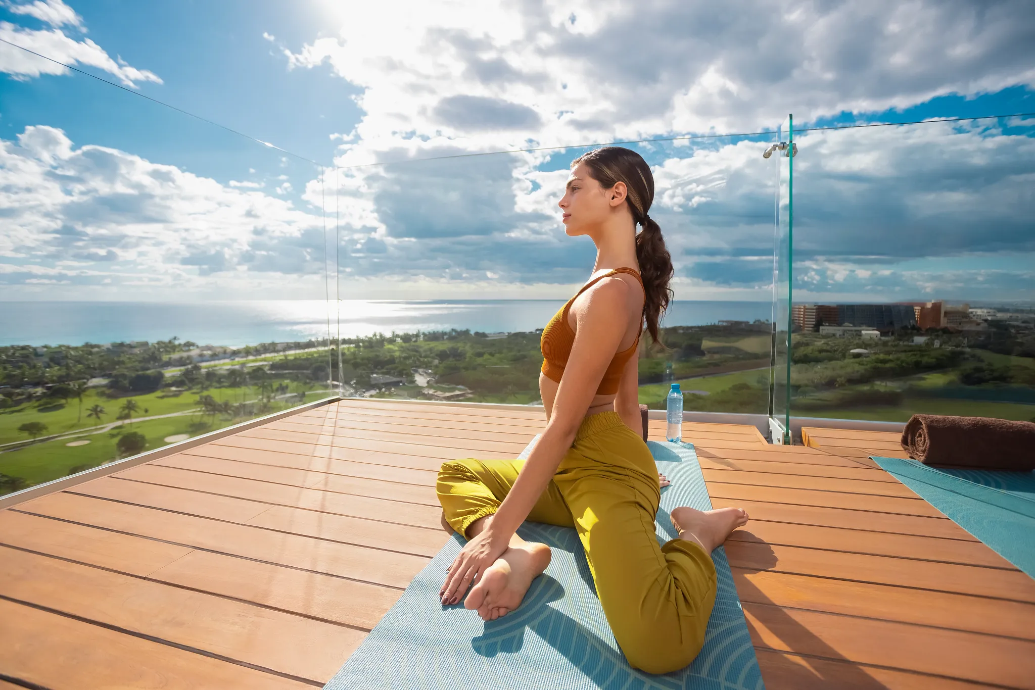 Woman practicing yoga on a rooftop deck with ocean views at Hyatt Vivid Grand Island.