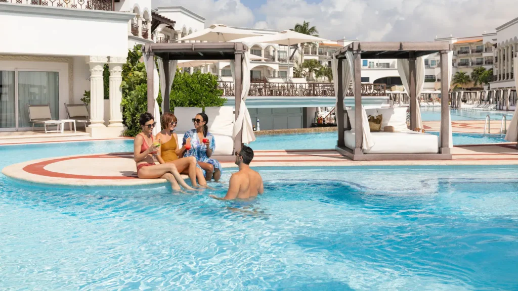 Friends enjoying cocktails in the main pool area at Hyatt Vivid Playa del Carmen with luxury cabanas nearby.
