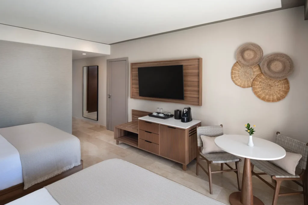 Deluxe Garden View room seating area with TV, coffee station, and modern wood furnishings at Hyatt Vivid Punta Cana.