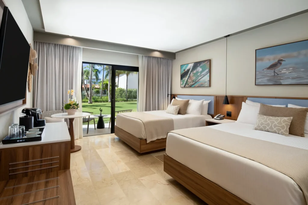 Spacious double queen guest room with garden view terrace at Hyatt Vivid Punta Cana, featuring modern decor and natural light.