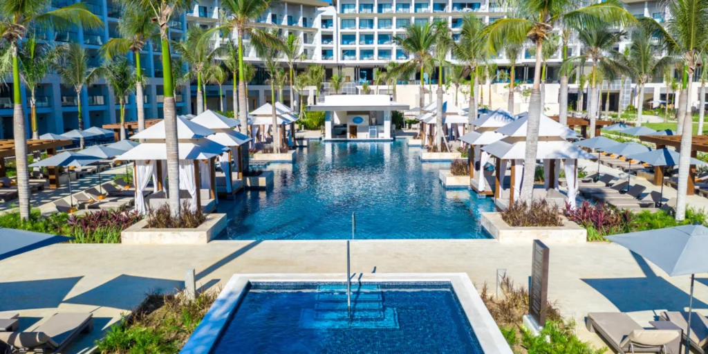 Expansive resort pools surrounded by palm trees and luxury cabanas at Hyatt Zilara Cap Cana.