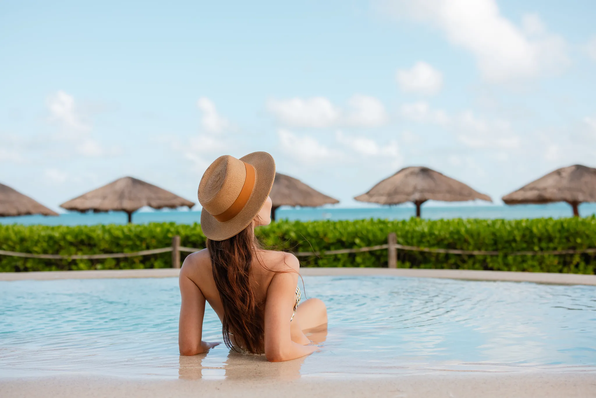 Woman relaxing in a beachfront infinity pool overlooking the Caribbean Sea at Hyatt Zilara Riviera Maya.