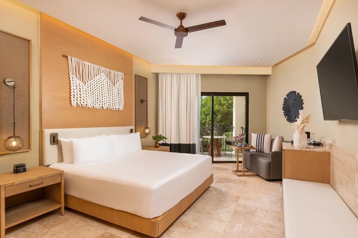 Junior Suite Tropical View King bedroom with seating area and balcony at Hyatt Zilara Riviera Maya.