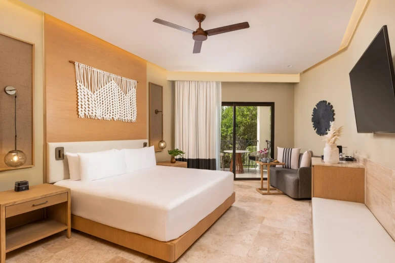 Junior Suite Tropical View King bedroom with seating area and balcony at Hyatt Zilara Riviera Maya.