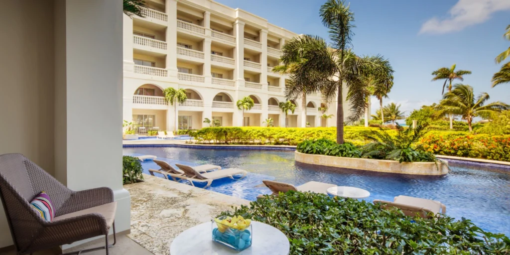 Swim-up suite patio overlooking a lazy river-style pool and tropical gardens at Hyatt Zilara Rose Hall in Montego Bay.
