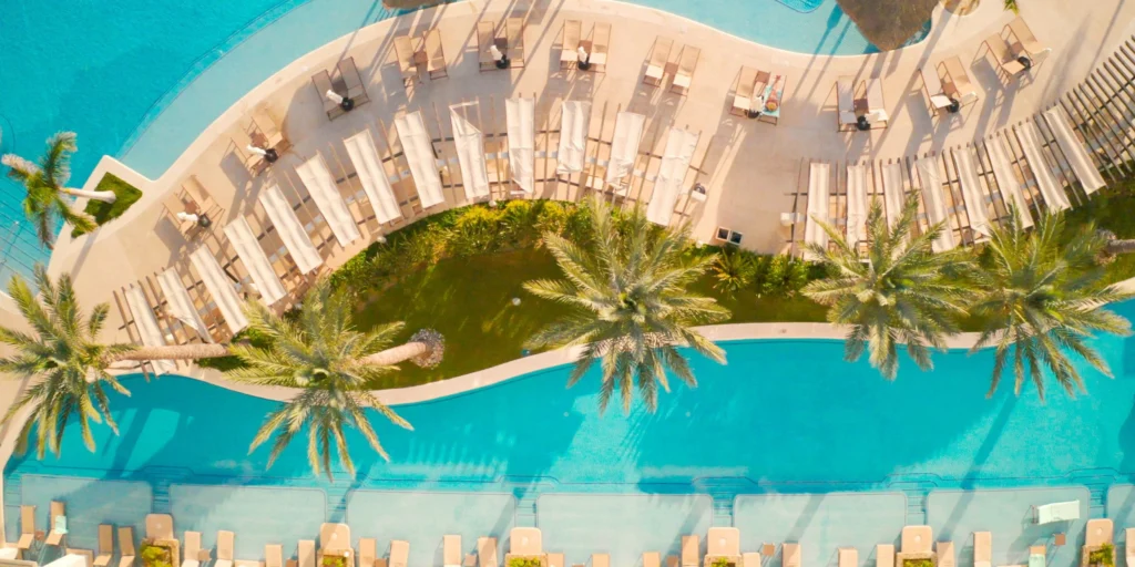 Aerial view of Hyatt Ziva Los Cabos pools, palm trees, and beachfront resort.