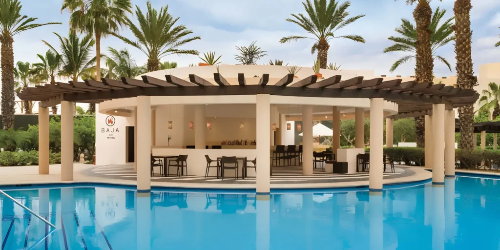 Swim-up Baja Bar at Hyatt Ziva Los Cabos surrounded by crystal-clear pools and tropical palm trees.