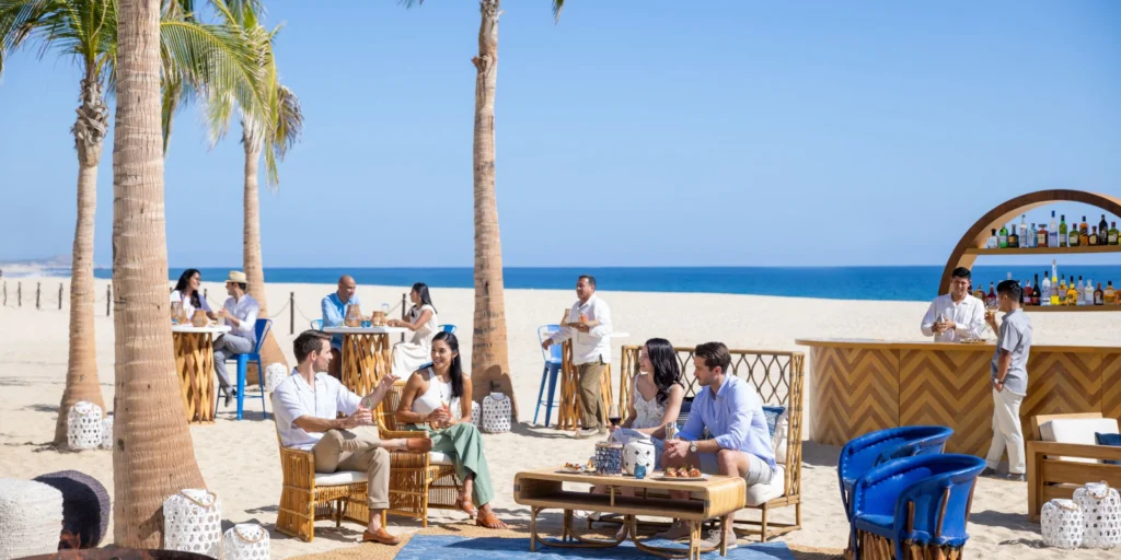 Guests relaxing with drinks at the beachfront lounge area at Hyatt Ziva Los Cabos.