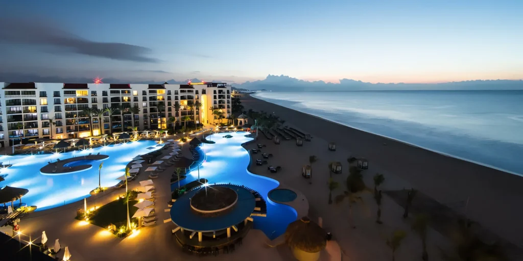 Evening aerial view of Hyatt Ziva Los Cabos beachfront resort illuminated at night.