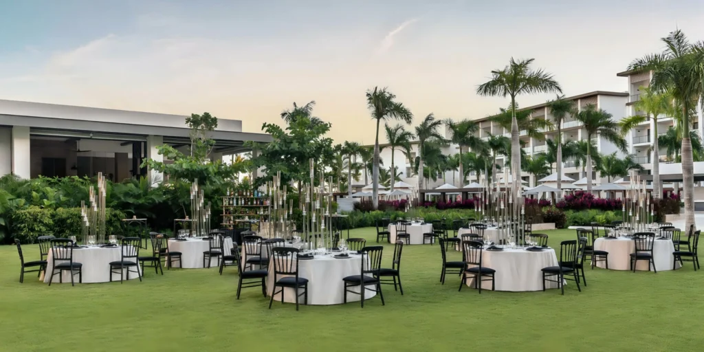 Outdoor wedding reception setup on a manicured lawn at Hyatt Ziva Cap Cana featuring elegant tables, tropical landscaping, and resort views.
