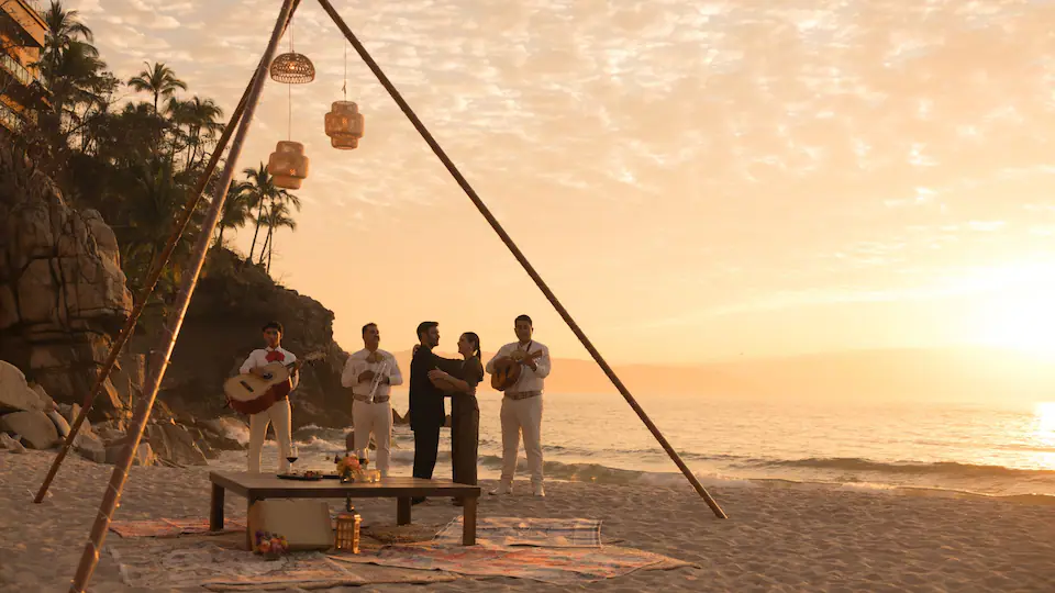 Couple enjoying a private beachfront dinner with live mariachi music at Hyatt Ziva Puerto Vallarta during sunset.