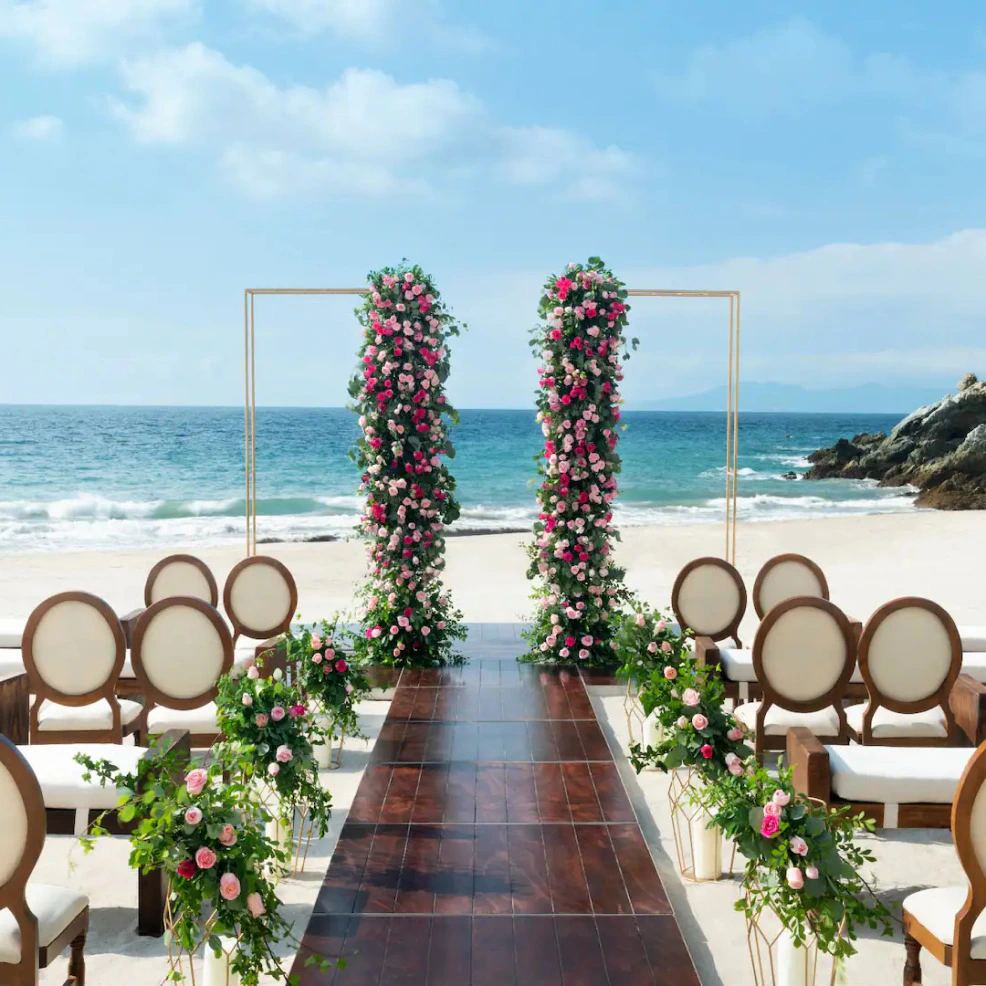 Romantic beachfront wedding setup at Hyatt Ziva Puerto Vallarta with floral arch and ocean views.