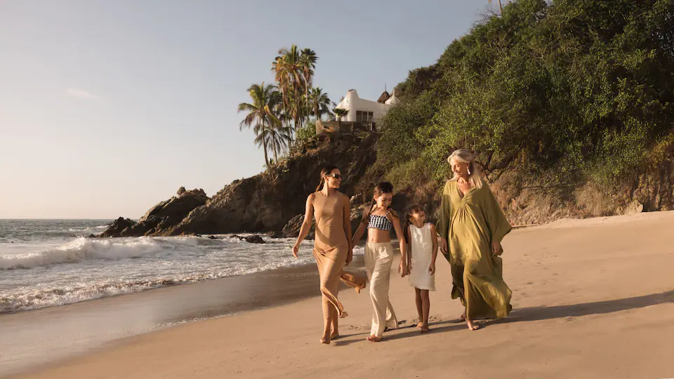 Family enjoying a scenic walk along the beach at Hyatt Ziva Puerto Vallarta surrounded by tropical landscapes.