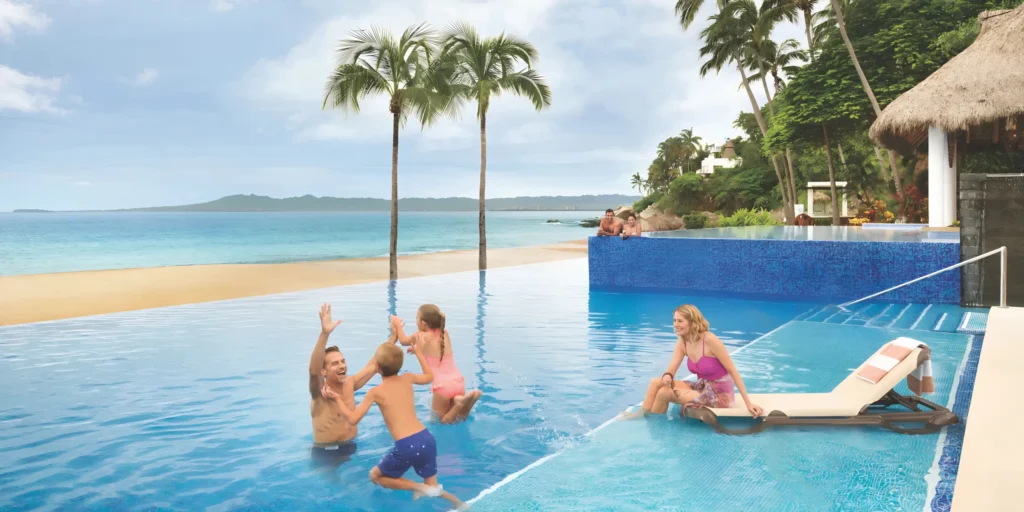 Family enjoying quality time in the beachfront infinity pool at Hyatt Ziva Puerto Vallarta, overlooking the Pacific Ocean and private beach.