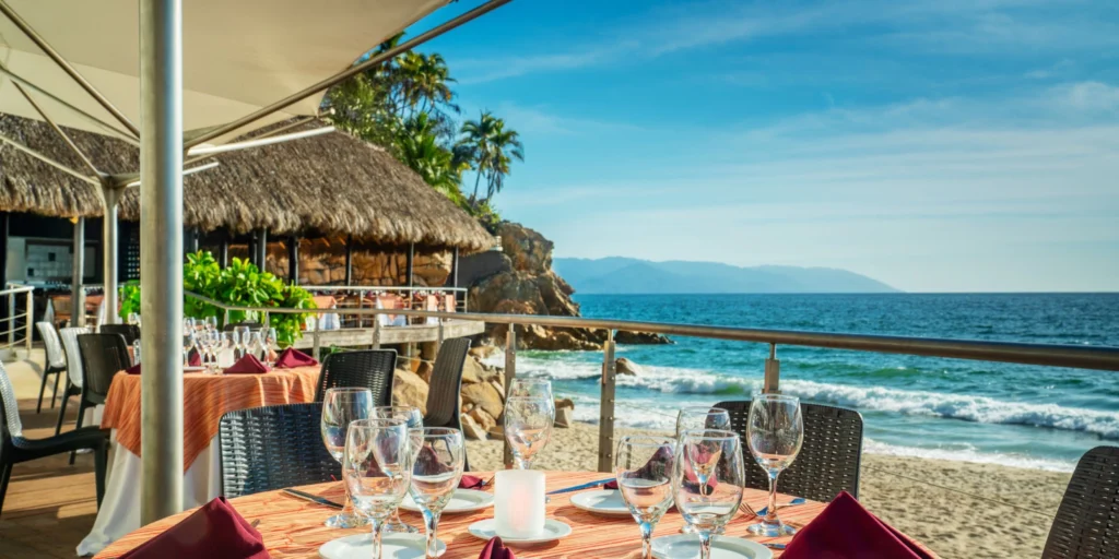 Oceanfront dining terrace at Hyatt Ziva Puerto Vallarta with tables overlooking the beach and Pacific Ocean.
