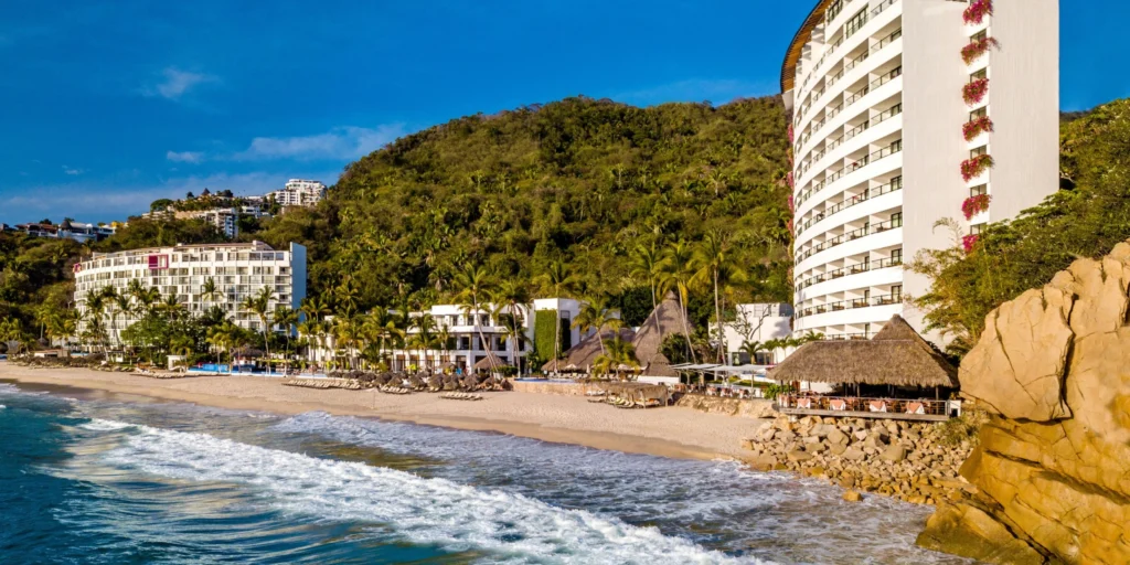 Exterior view of Hyatt Ziva Puerto Vallarta nestled between the Pacific Ocean and lush tropical mountains.