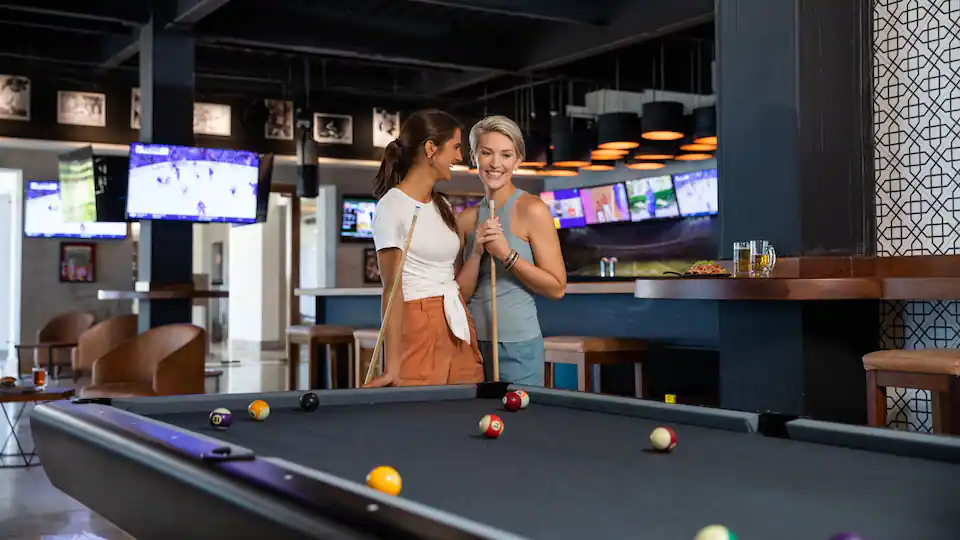 Guests playing billiards and enjoying entertainment at the sports bar at Hyatt Ziva Puerto Vallarta.