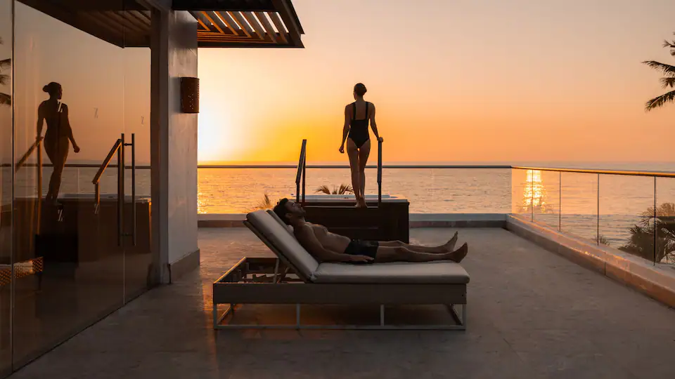 Couple relaxing at the spa terrace during sunset at Hyatt Ziva Puerto Vallarta with panoramic ocean views.