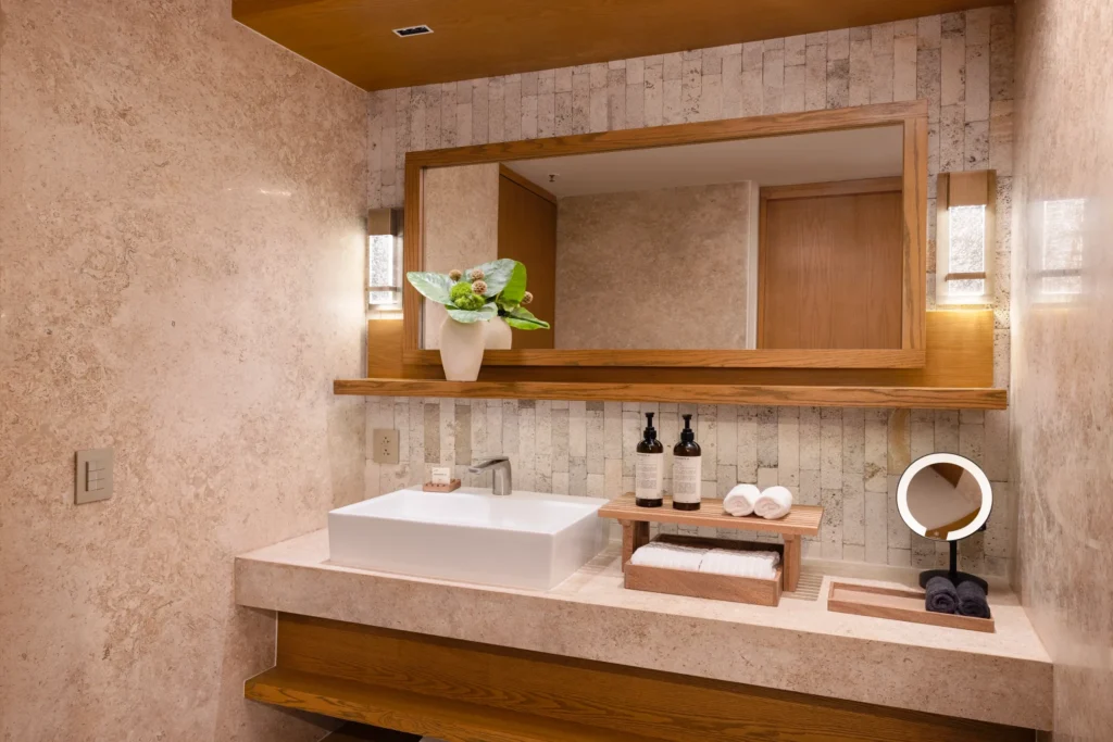 Junior Suite King bathroom with modern sink, rain shower, and natural stone finishes at Impression Isla Mujeres by Secrets.