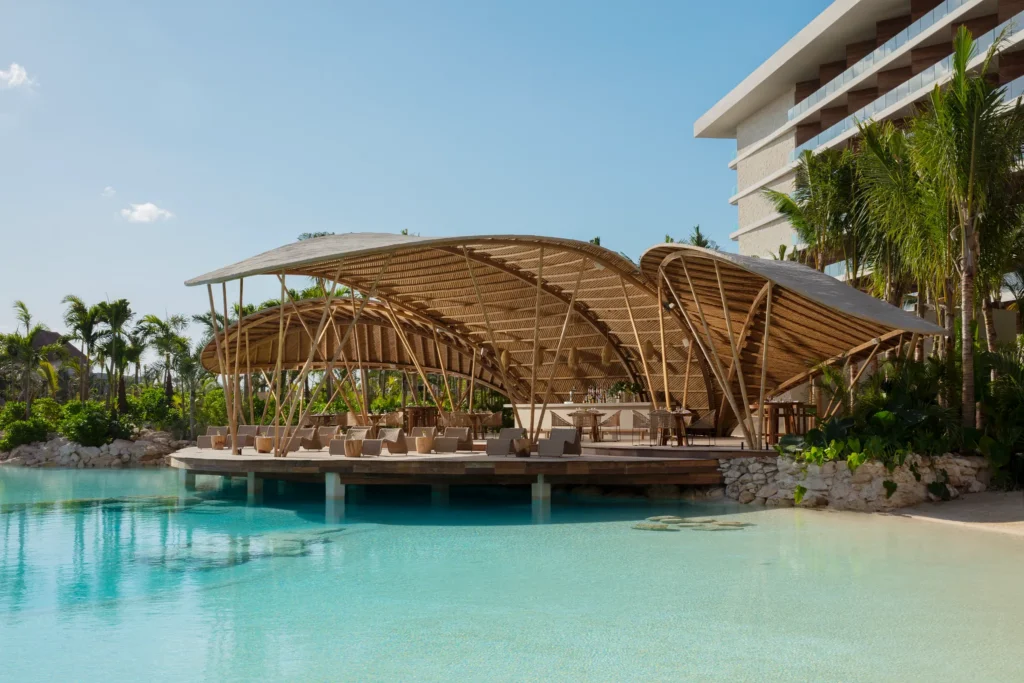 Bamboo restaurant at Impression Moxché by Secrets featuring a stunning over-water terrace, bamboo architecture, and turquoise lagoon views.