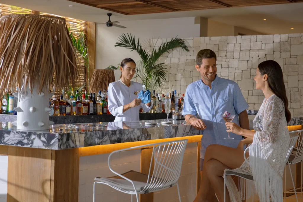 Couple enjoying cocktails at the beach club bar at Impression Moxché by Secrets in Playa del Carmen.