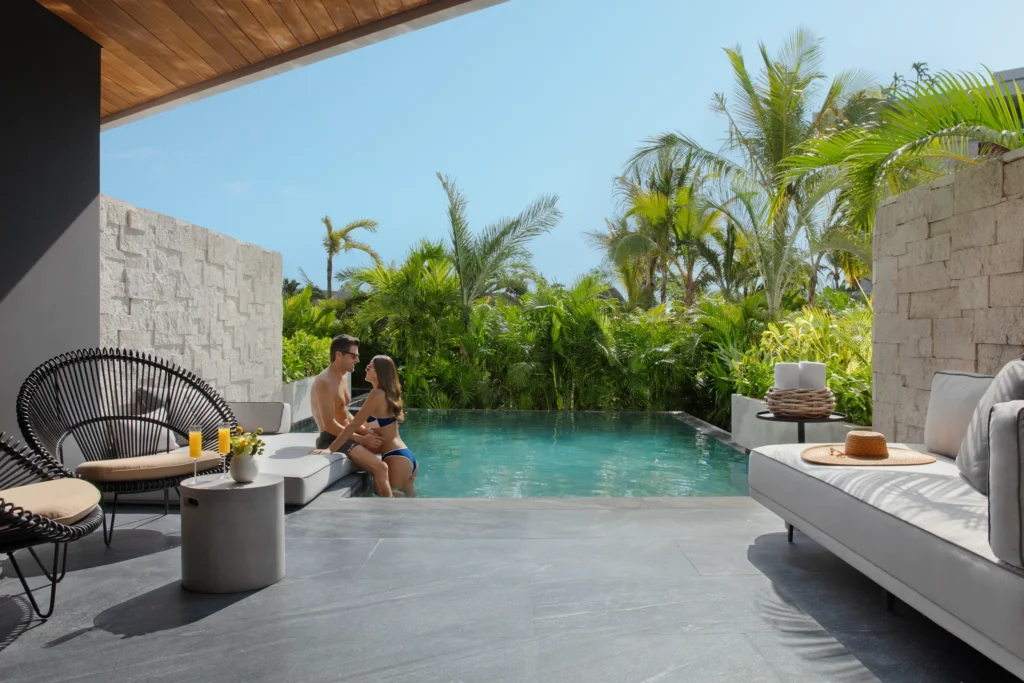 Couple relaxing in a private swim-out suite pool at Impression Moxché by Secrets surrounded by tropical greenery.