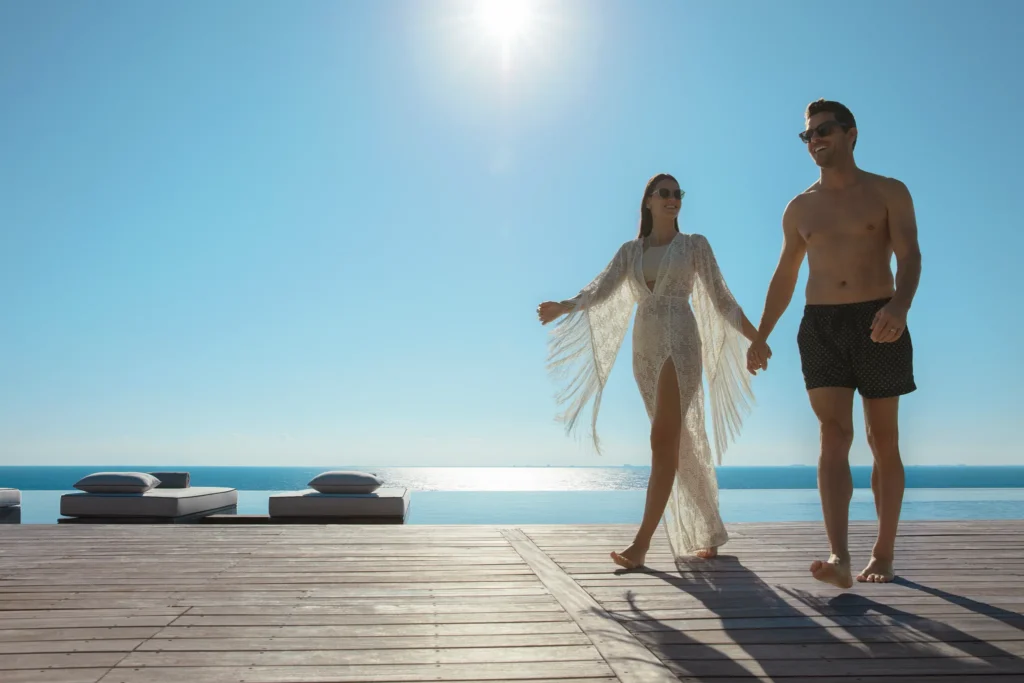Couple walking hand-in-hand near rooftop infinity pool at Impression Moxché by Secrets.