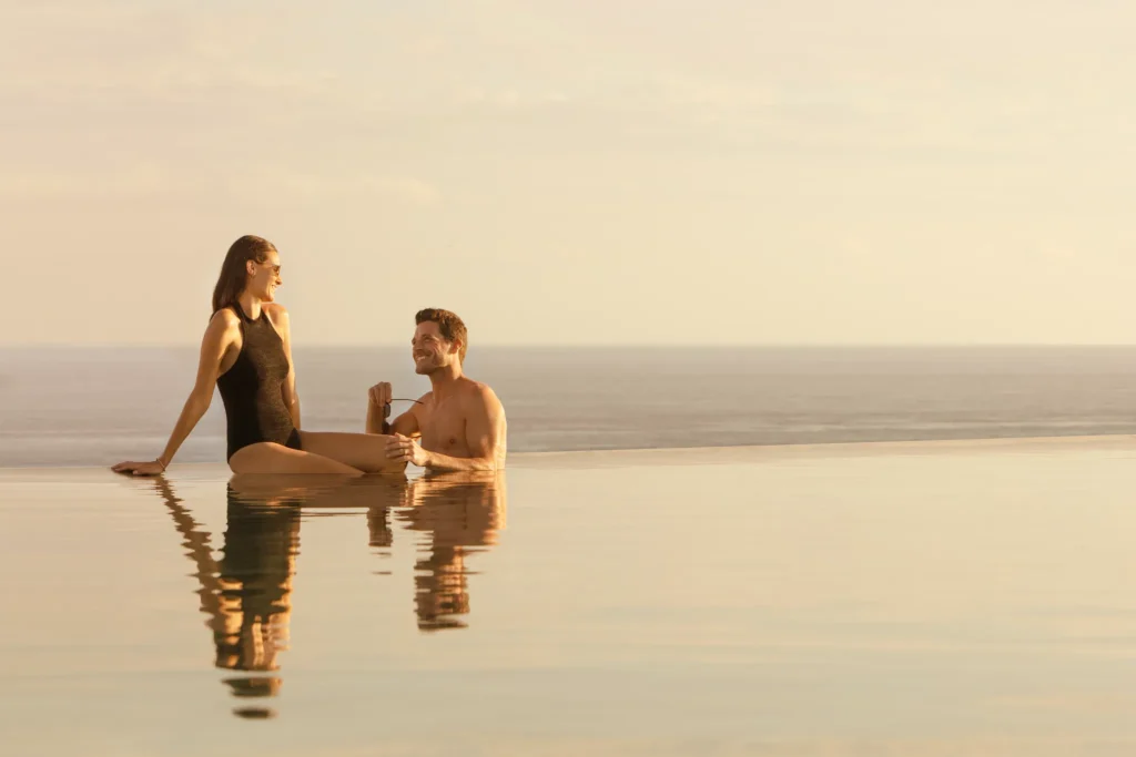 Couple relaxing in an infinity pool at sunset at Impression Moxché by Secrets.