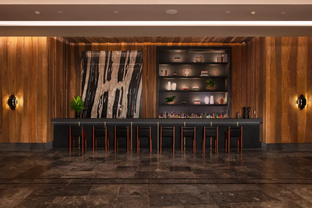 Moxché Lobby Bar at Impression Moxché by Secrets featuring sleek dark marble bar, warm wood accents, and modern upscale ambiance.