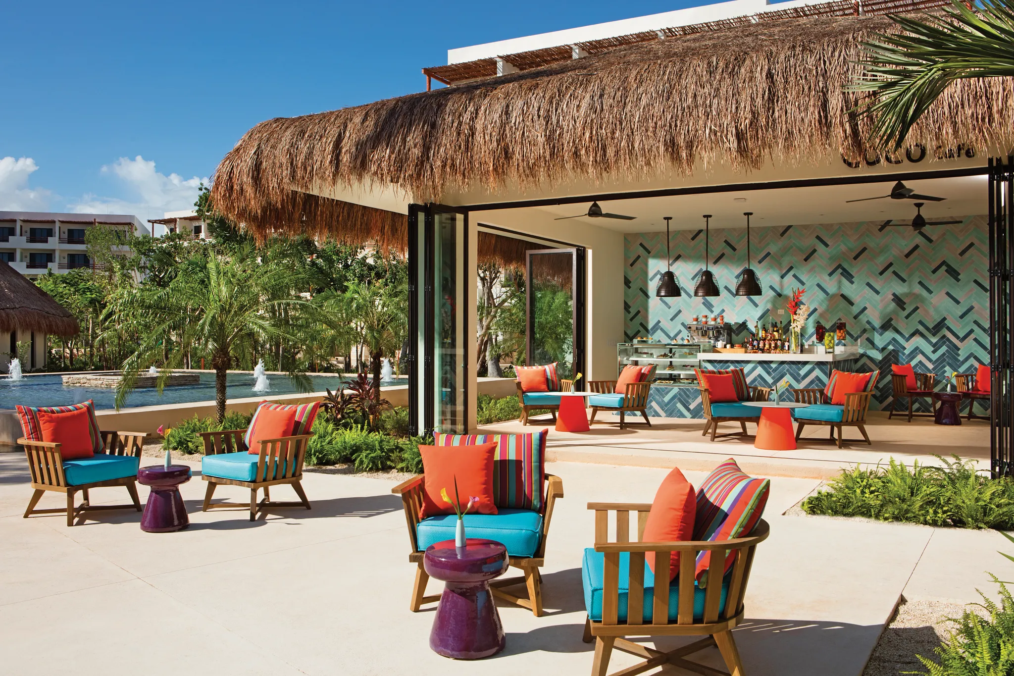 Coco Café at Secrets Akumal Riviera Maya featuring an open-air premium coffee bar with colorful lounge seating, tropical décor, and a relaxed resort atmosphere.