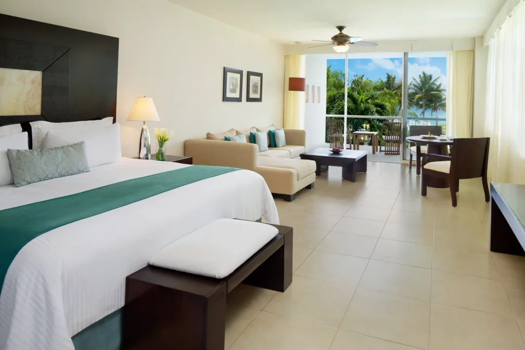 Junior Suite Ocean View Terrace with king bed, living area, and balcony overlooking the ocean at Secrets Aura Cozumel.