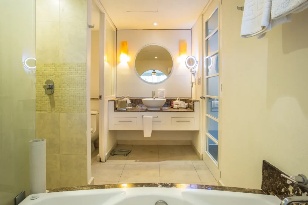 Bathroom vanity with sink and illuminated mirror in Junior Suite Ocean View at Secrets Aura Cozumel.