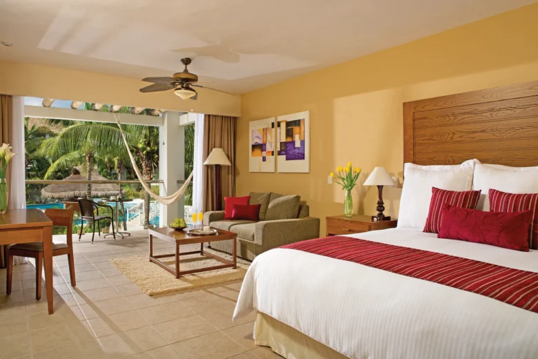 Junior Suite with king bed, furnished balcony with hammock, and pool view at Secrets Aura Cozumel Resort.