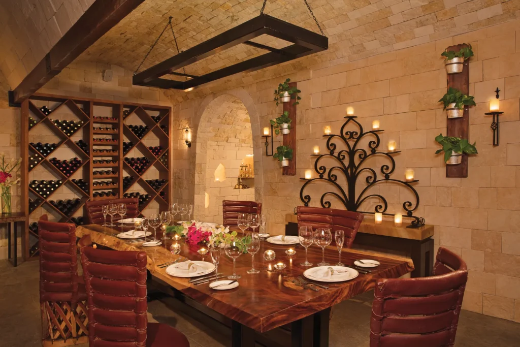 La Cava private dining at Secrets Aura Cozumel featuring an elegant wine cellar, intimate table setting, and premium wine selections.