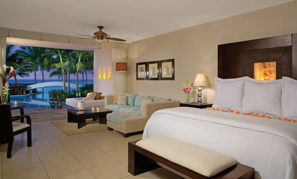 Preferred Club Junior Suite Swim-Up Ocean View at night with lit terrace and ocean backdrop at Secrets Aura Cozumel.