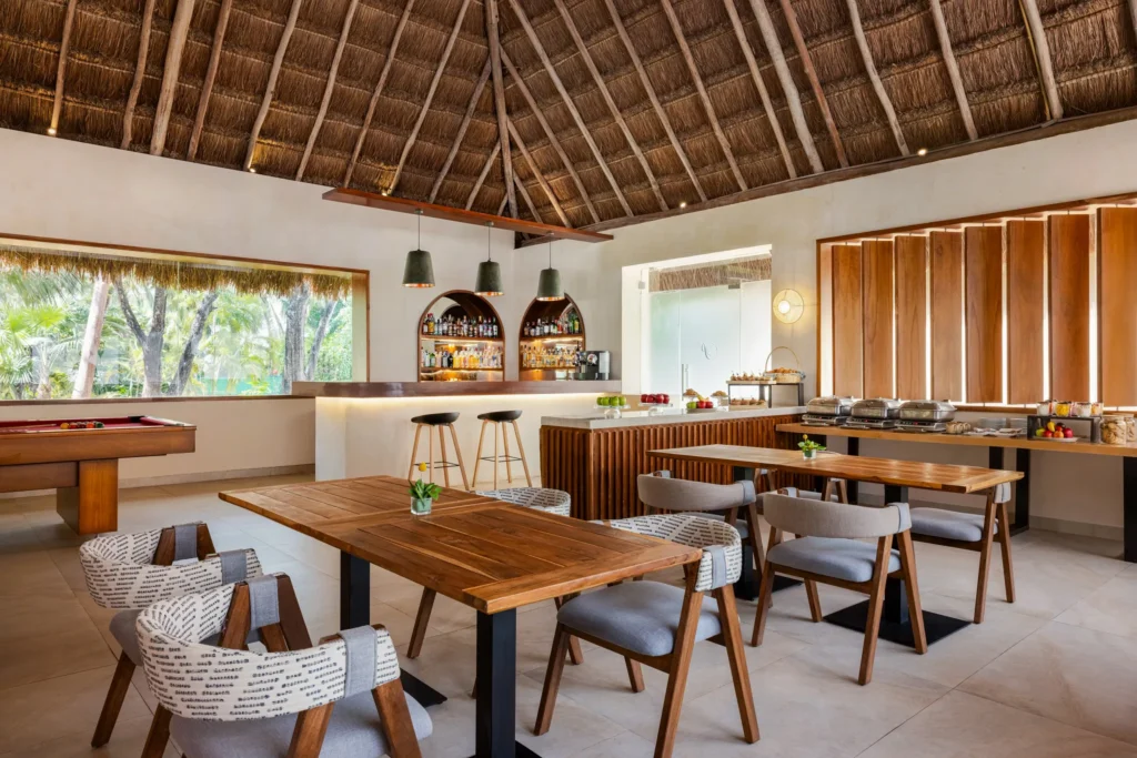 Preferred Club lounge dining area with buffet setup and wooden decor at Secrets Aura Cozumel.