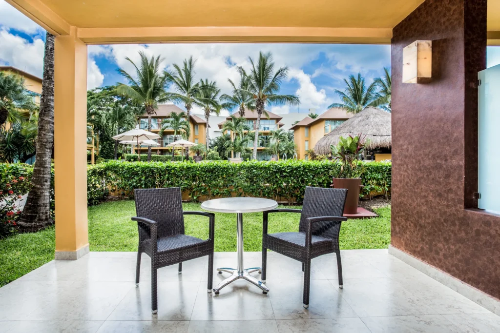 Private furnished terrace with seating and garden pool view at Secrets Aura Cozumel.