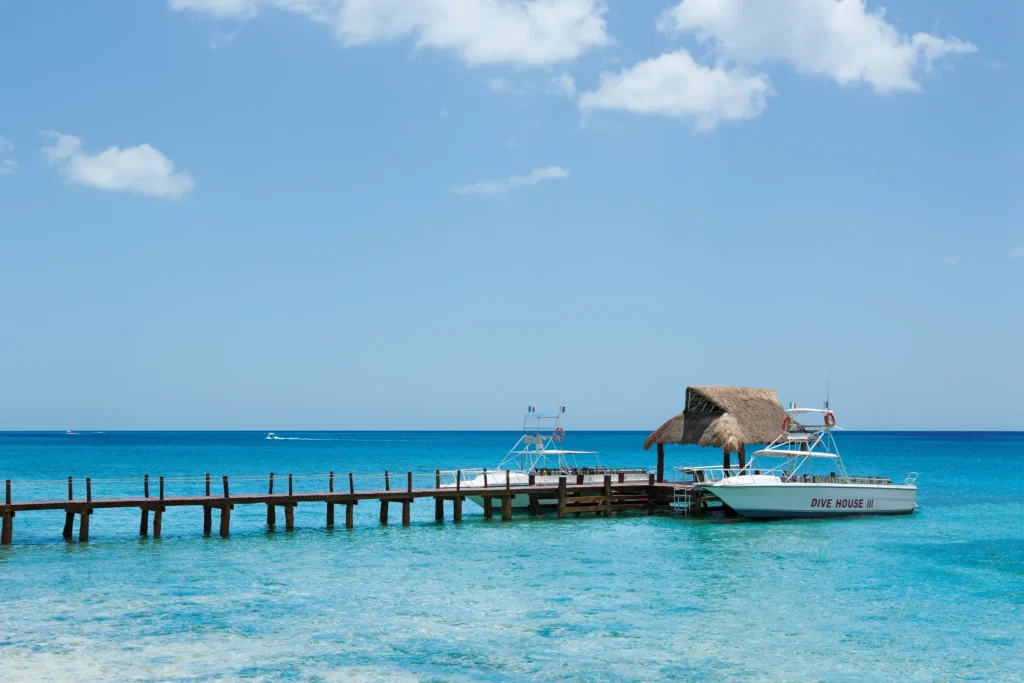 Dive boats docked at pier at Secrets Aura Cozumel over clear Caribbean water.