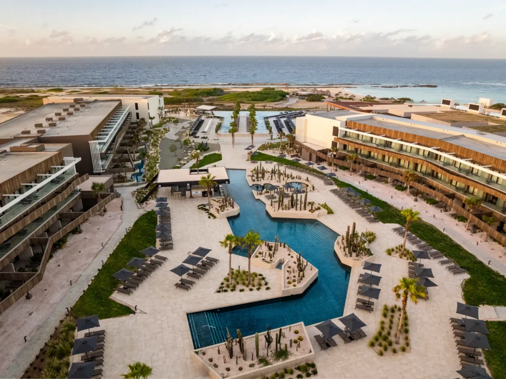 Aerial view of the pool complex and lounge areas at Secrets Baby Beach Aruba near the ocean.