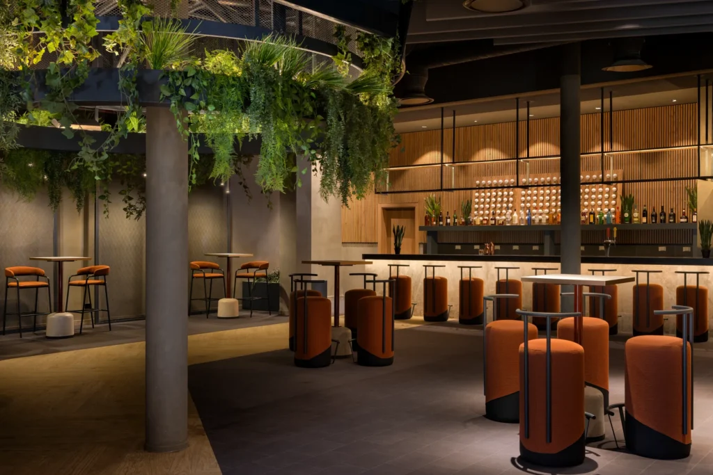 Desire Music Lounge at Secrets Baby Beach Aruba featuring a stylish bar, modern lounge seating, indoor greenery, and contemporary nightlife ambiance.