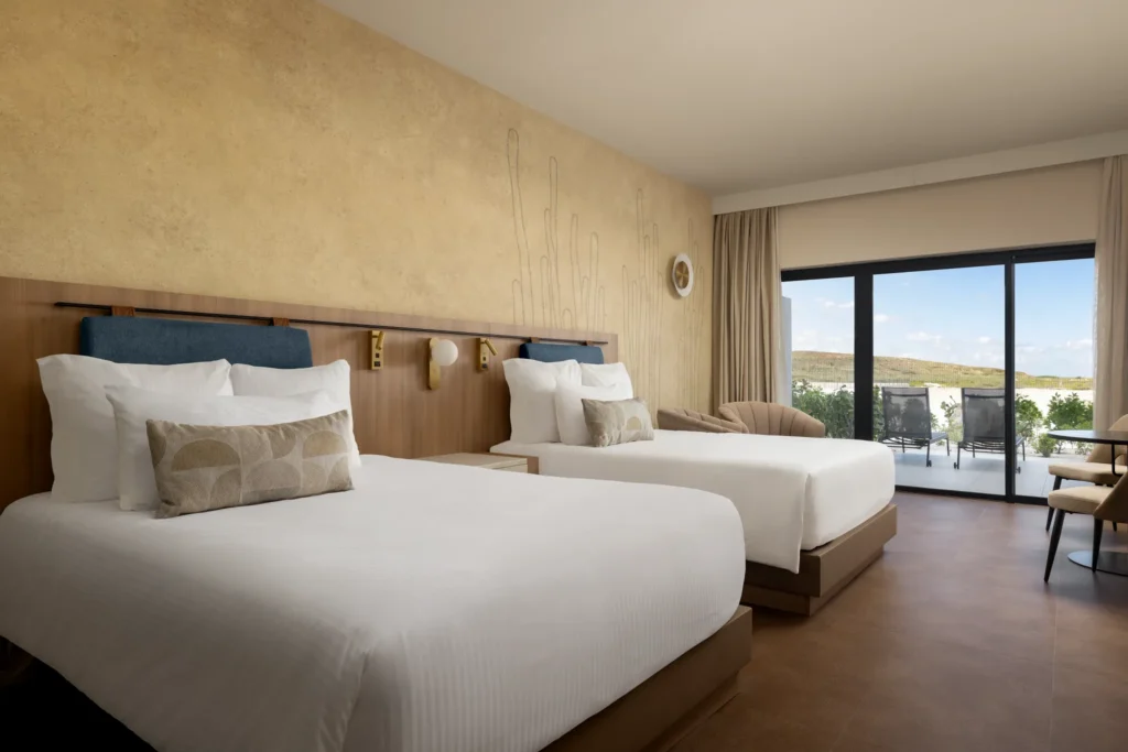 Junior Suite with two double beds and private balcony at Secrets Baby Beach Aruba.