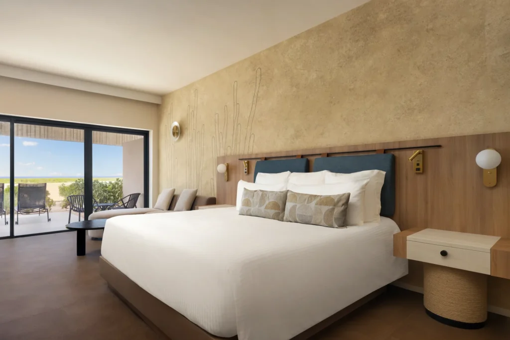 Junior Suite king bedroom with seating area and balcony at Secrets Baby Beach Aruba.