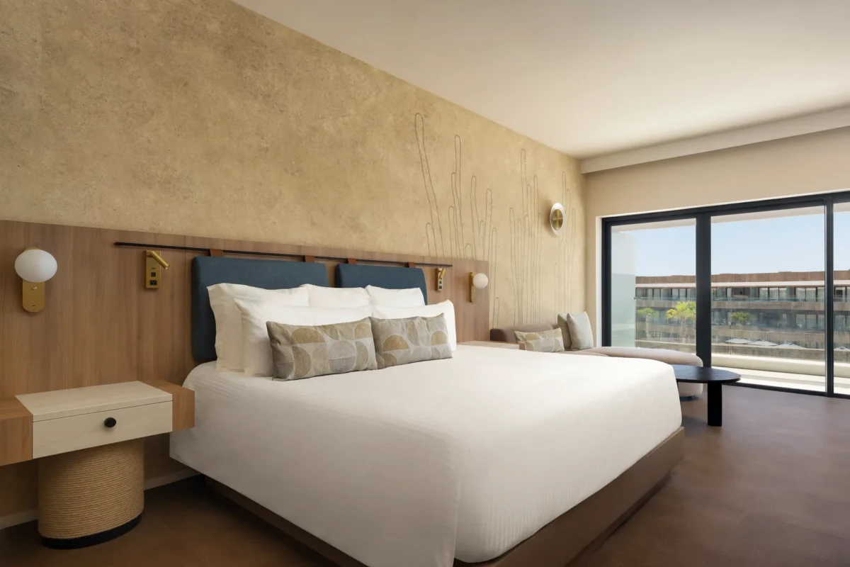 Junior Suite Pool View with king-size bed and balcony overlooking the pool at Secrets Baby Beach Aruba.