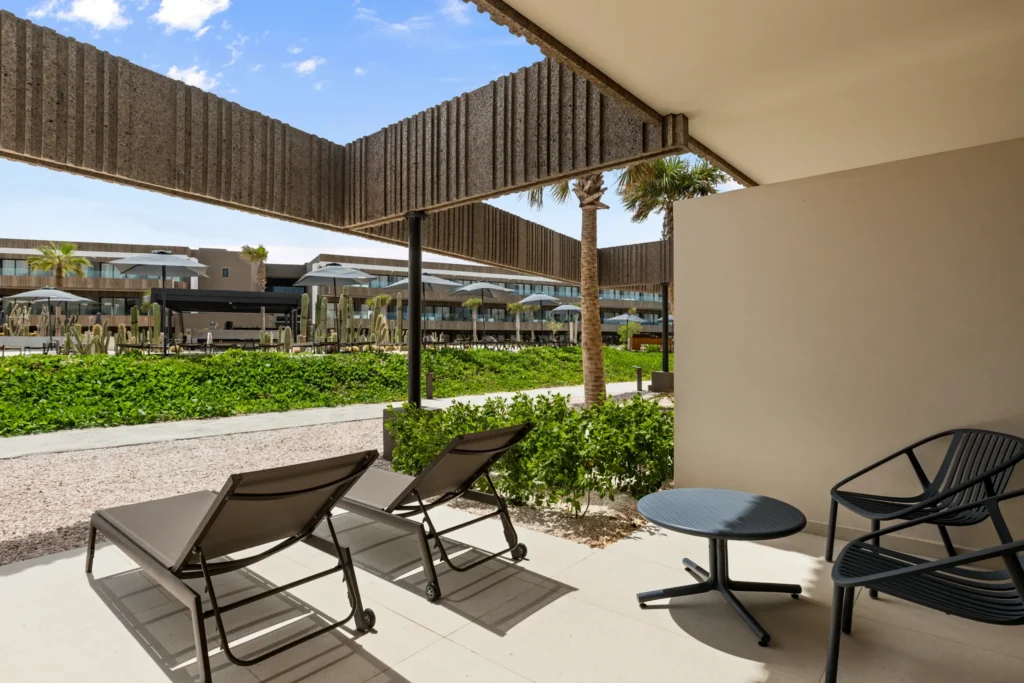 Junior Suite Poolside Terrace with lounge chairs and direct pool access at Secrets Baby Beach Aruba.