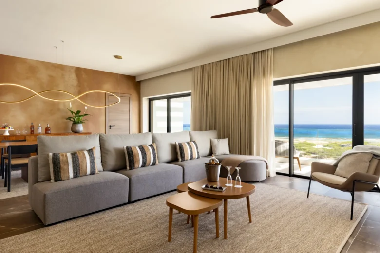 Preferred Club Presidential Suite Ocean View living area with sofa bed and dining space at Secrets Baby Beach Aruba.