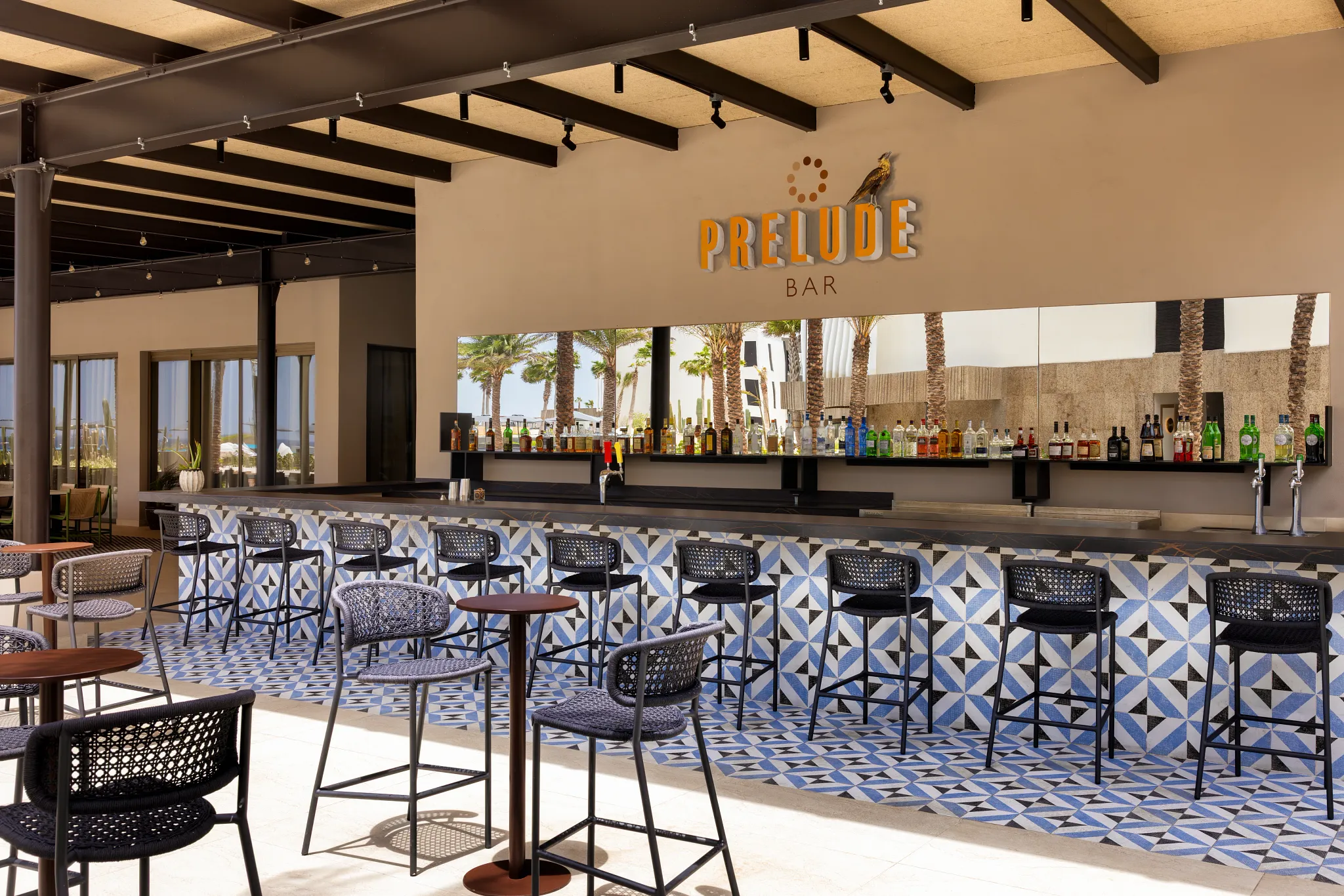 Prelude Bar at Secrets Baby Beach Aruba featuring an open-air bar with patterned tile design, high-top seating, and tropical ambiance.