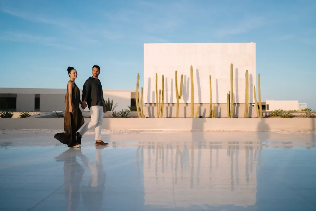Stylish couple walking through the modern resort grounds at Secrets Baby Beach Aruba.