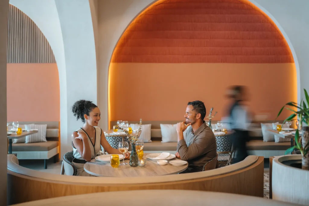 Couple dining in a romantic restaurant with warm ambient lighting at Secrets Baby Beach Aruba.