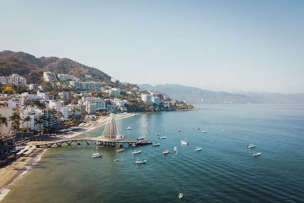 Playa de los Muertos near Secrets Bahia Mita Surf & Spa Resort with iconic pier, beachfront boats, and Puerto Vallarta coastline